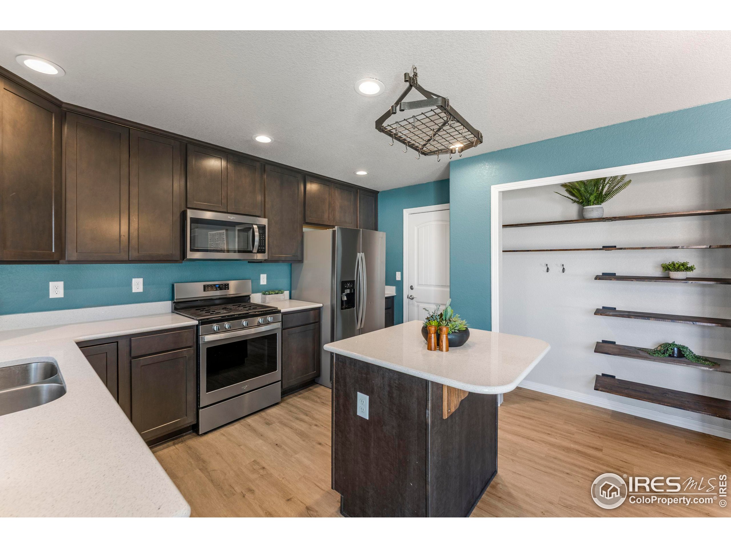 4527 Longmead Drive Windsor, CO 80550 - Photo 9 of 32 a kitchen with stainless steel appliances kitchen island granite countertop a refrigerator a stove a sink dishwasher and a dining table with wooden floor