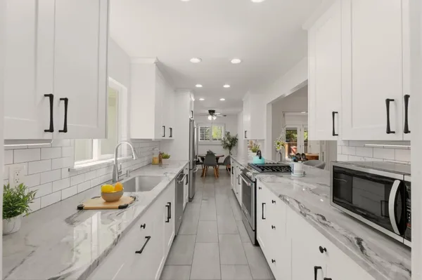 a kitchen with a sink dishwasher stove and white cabinets with wooden floor