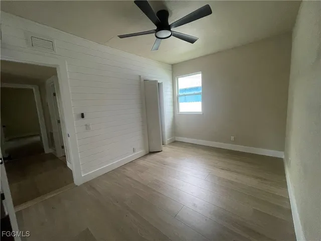an empty room with windows a fireplace a ceiling fan and wooden floor