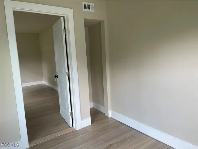 an empty room with wooden floor cabinet and windows