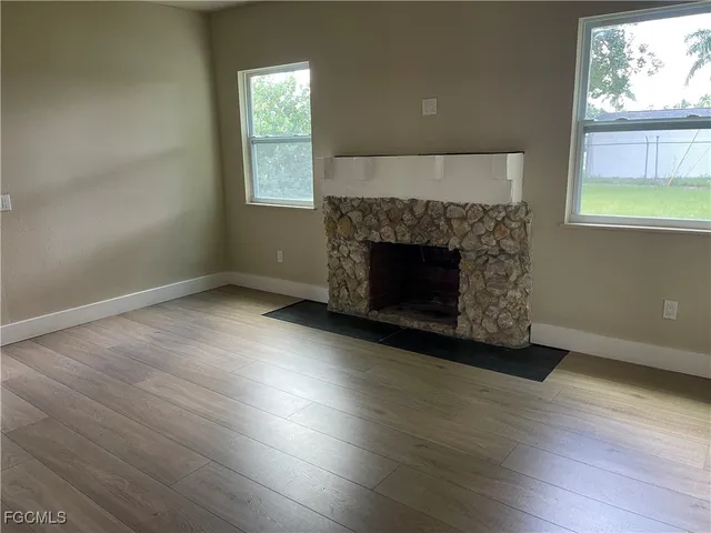 an empty room with windows a fireplace and wooden floor
