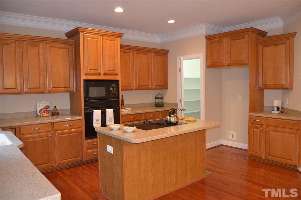 8425 Henderson Road Apex, NC 27539 - Photo 7 of 25 a kitchen with stainless steel appliances granite countertop a stove a sink dishwasher and a refrigerator with wooden floor