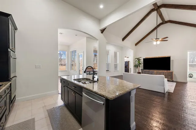 a view of living room kitchen with stainless steel appliances granite countertop furniture and a flat screen tv