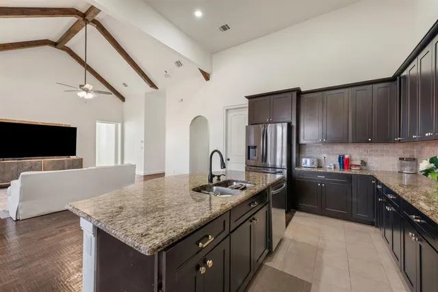 a kitchen with stainless steel appliances granite countertop a sink dishwasher stove and refrigerator with wooden floor
