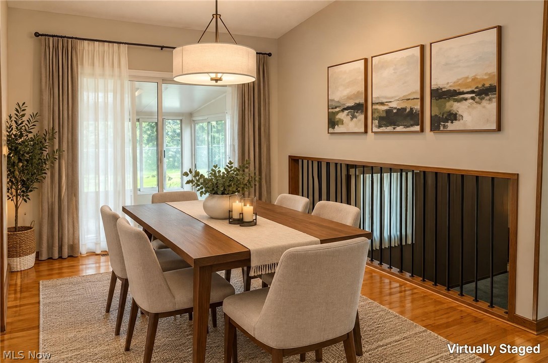 2848 Pressler Road Uniontown, OH 44685 - Photo 21 of 37 Vaulted ceiling with drum pendant lighting, hardwood flooring, and sliding glass doors leading to a sunroom