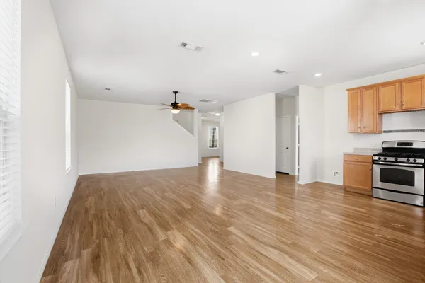 a view of empty room with wooden floor and kitchen