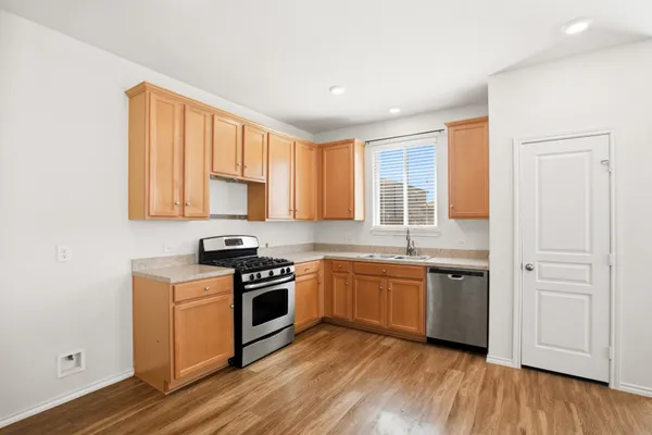 a kitchen with stainless steel appliances granite countertop hardwood floor sink stove and wooden cabinets