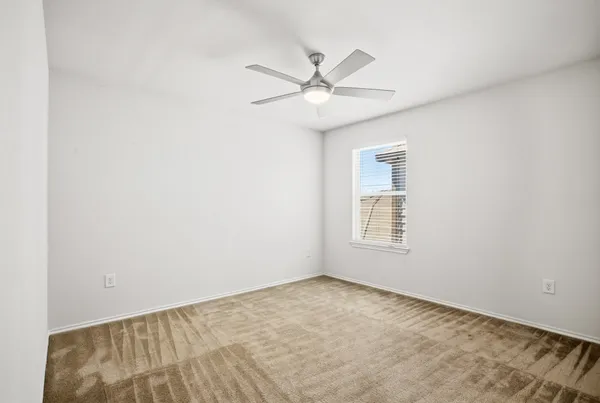 an empty room with a window and ceiling fan