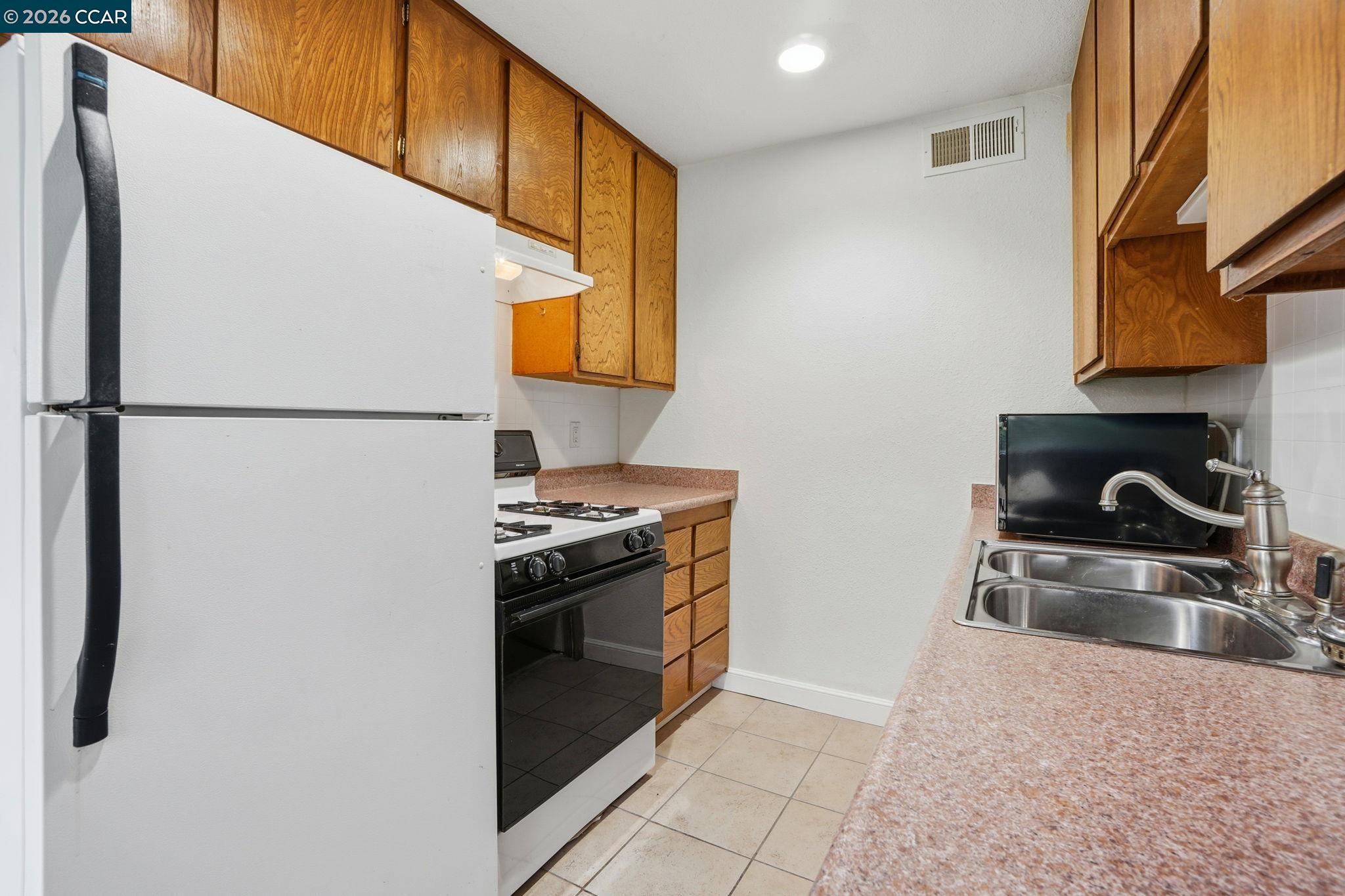 1160 Kenwal Road, Unit D Concord, CA 94521 - Photo 11 of 38 a kitchen with stainless steel appliances granite countertop a refrigerator a stove and a sink with wooden cabinets