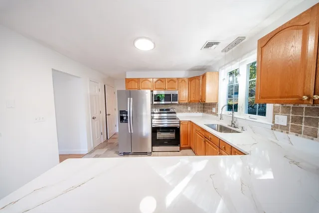 a kitchen with stainless steel appliances granite countertop a refrigerator a stove and a sink with cabinets