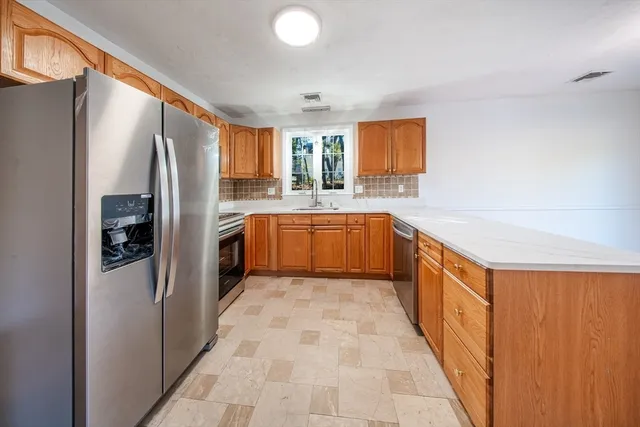 a large kitchen with stainless steel appliances granite countertop a refrigerator and a sink