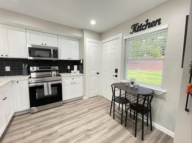 a kitchen with stainless steel appliances a stove a sink a microwave a dining table and chairs