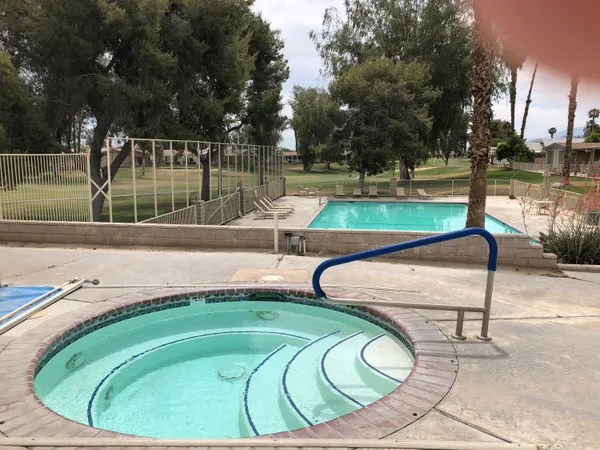 a view of a swimming pool with a lounge chair and trees