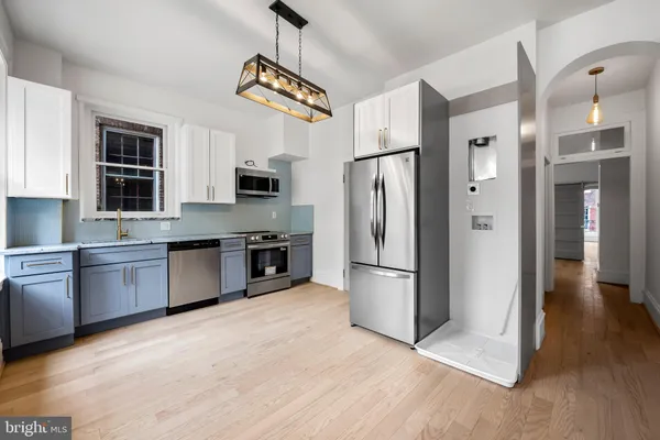 a kitchen with stainless steel appliances granite countertop a refrigerator a stove a sink dishwasher a oven with white cabinets and wooden floor