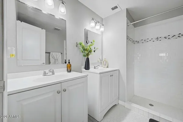 a bathroom with a sink double vanity granite tub shower and a mirror