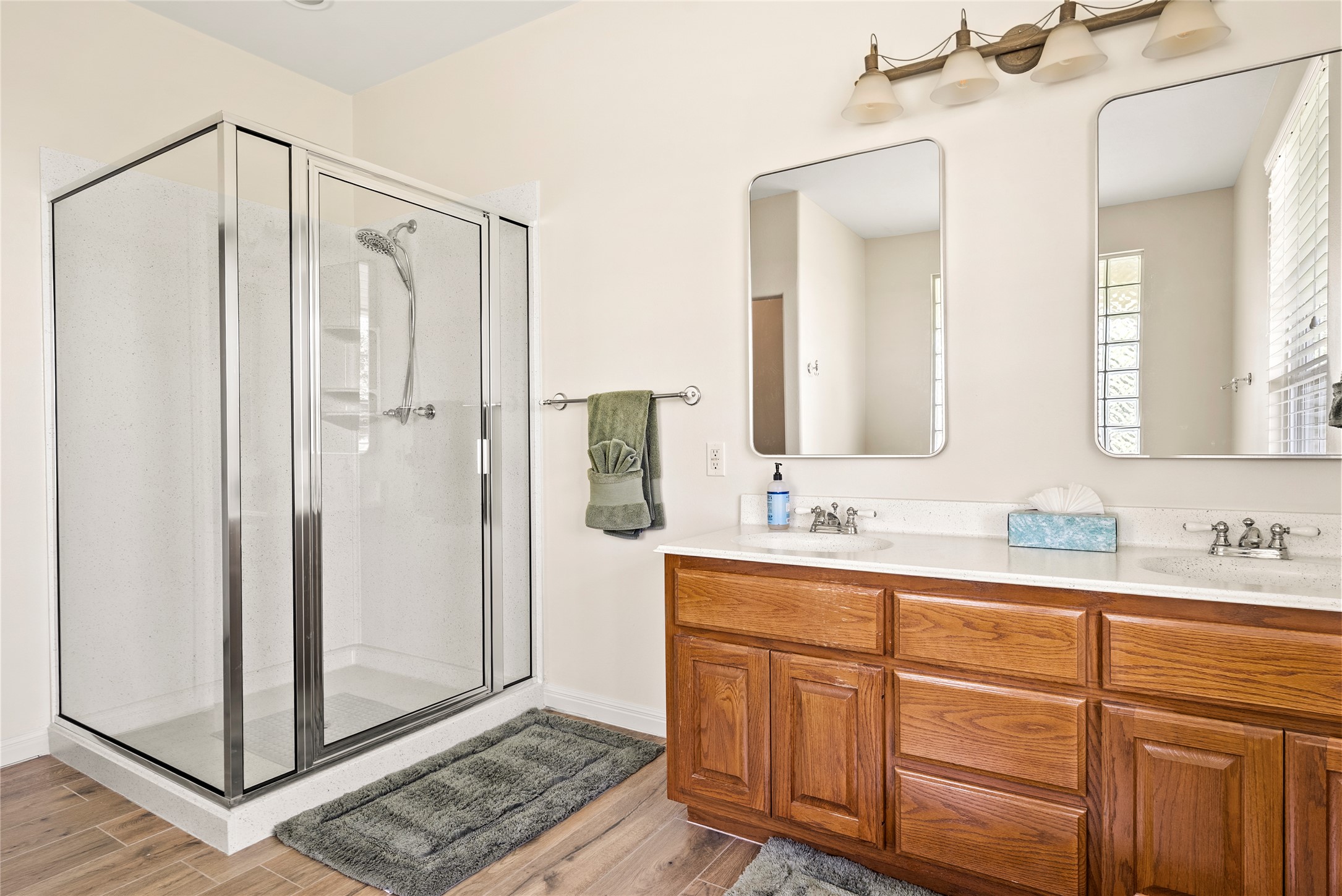 928 Upper Elgin River Road Elgin, TX 78621 - Photo 24 of 40 Bathroom featuring a glass-enclosed shower, dual vanities with integrated sinks, and wood-finish cabinetry.