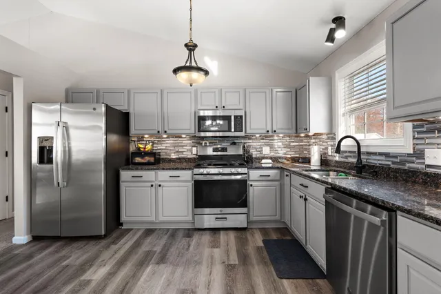 a kitchen with stainless steel appliances granite countertop a refrigerator a stove a sink dishwasher a microwave oven with a dining table and chairs