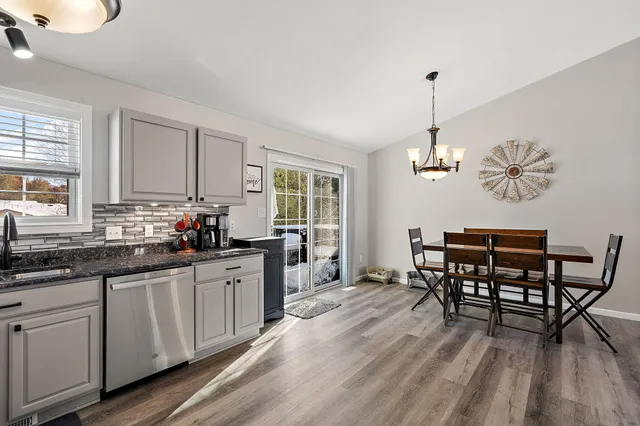 a kitchen with stainless steel appliances a dining table chairs and wooden floor
