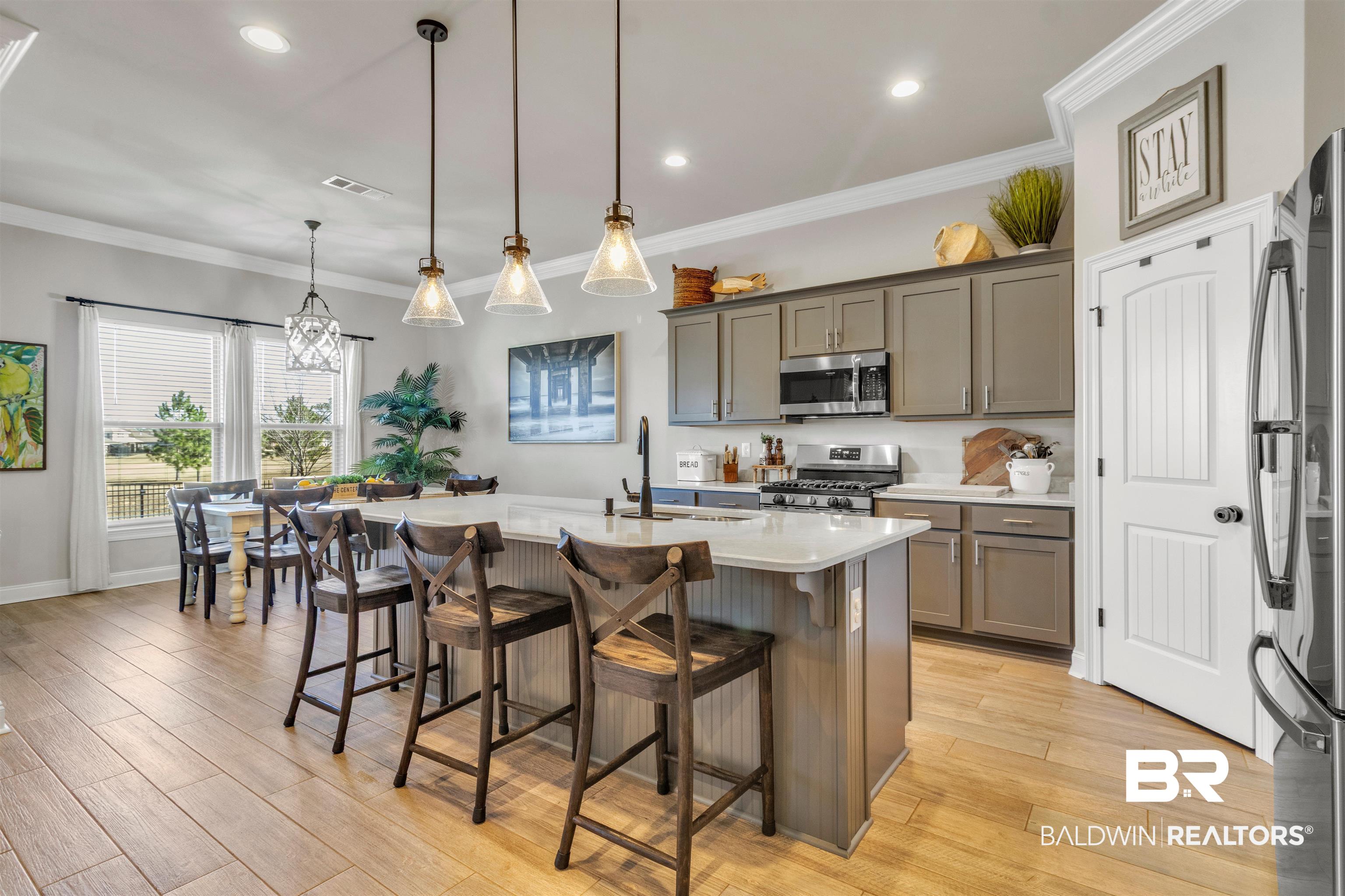 22531 Putter Lane Foley, AL 36535 - Photo 9 of 43 Kitchen featuring light wood-style floors, a breakfast bar, stainless steel appliances, a center island with sink, and crown molding