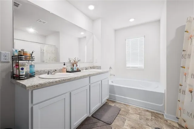 a bathroom with a granite countertop sink double vanity granite tub shower and a mirror
