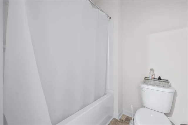a white toilet sitting next to a shower