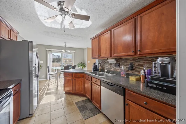 a kitchen with stainless steel appliances granite countertop a refrigerator a sink dishwasher a stove with wooden cabinets and floor