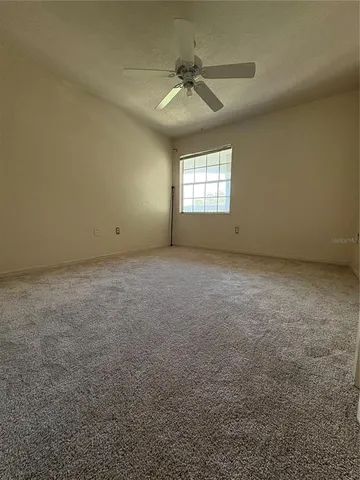 an empty room with a window and a ceiling fan