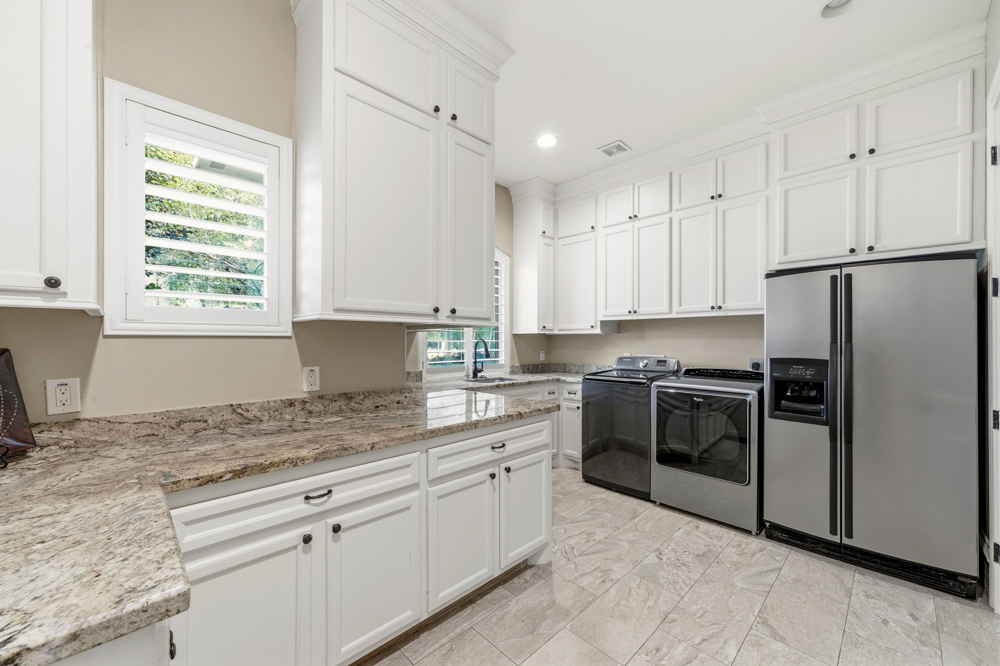 27402 Jacob's Path Lane Spring, TX 77386 - Photo 21 of 48 The spacious laundry room doubles as an exceptional back kitchen or prep space, offering abundant countertop workspace, a utility sink, and an additional refrigerator space. The window overlooks the front of the home and circular driveway, providing natural light and a welcoming view of guests as they arrive. Combining practicality with versatility, this well-designed space is ideal for entertaining, catering, or everyday household needs.