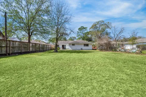 a view of a house with a big yard and large trees