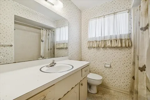 a bathroom with a toilet a sink a mirror and a window