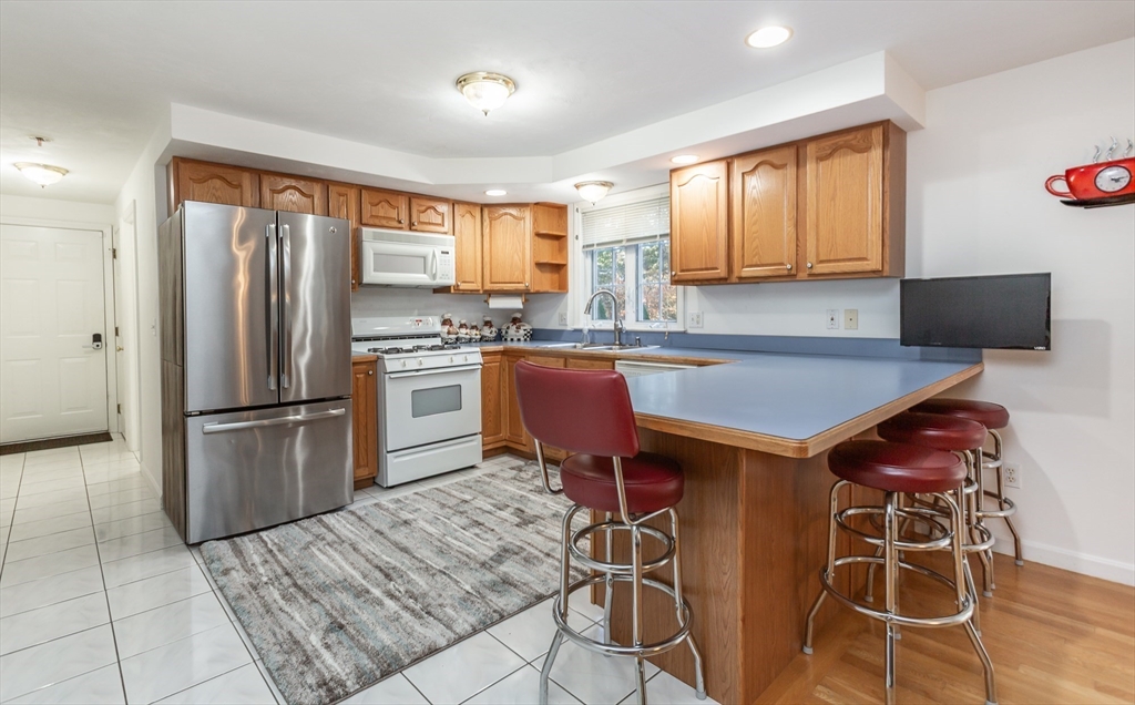 20 Sandy Way Mashpee, MA 02649 - Photo 8 of 33 a kitchen with stainless steel appliances granite countertop a stove a refrigerator a sink a dining table and chairs with wooden floor