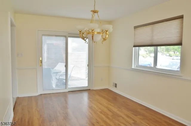 an empty room with wooden floor chandelier and windows