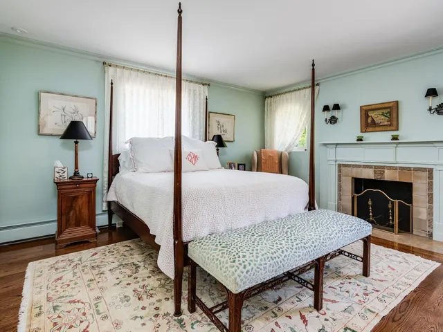 a bedroom with a bed a rug and a fireplace