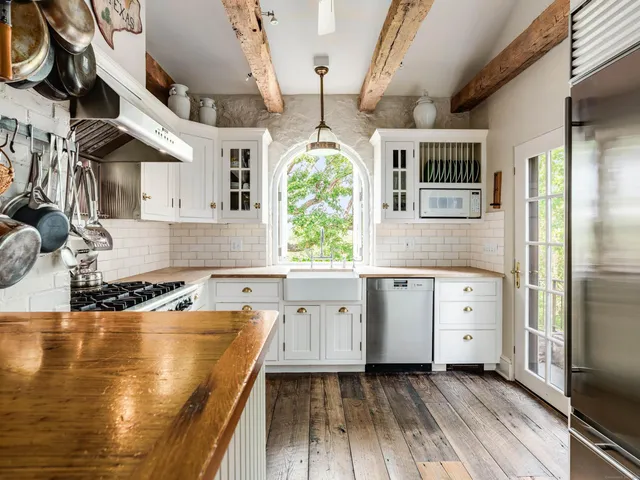 a kitchen with white cabinets and wooden floors