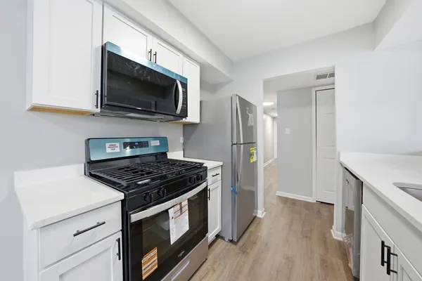 a kitchen with stainless steel appliances a stove a microwave and a hard wood floor