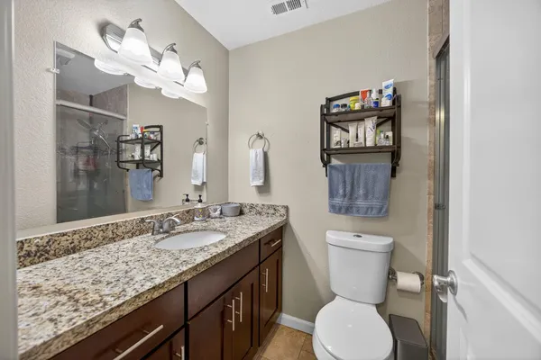 a bathroom with a granite countertop toilet sink and mirror