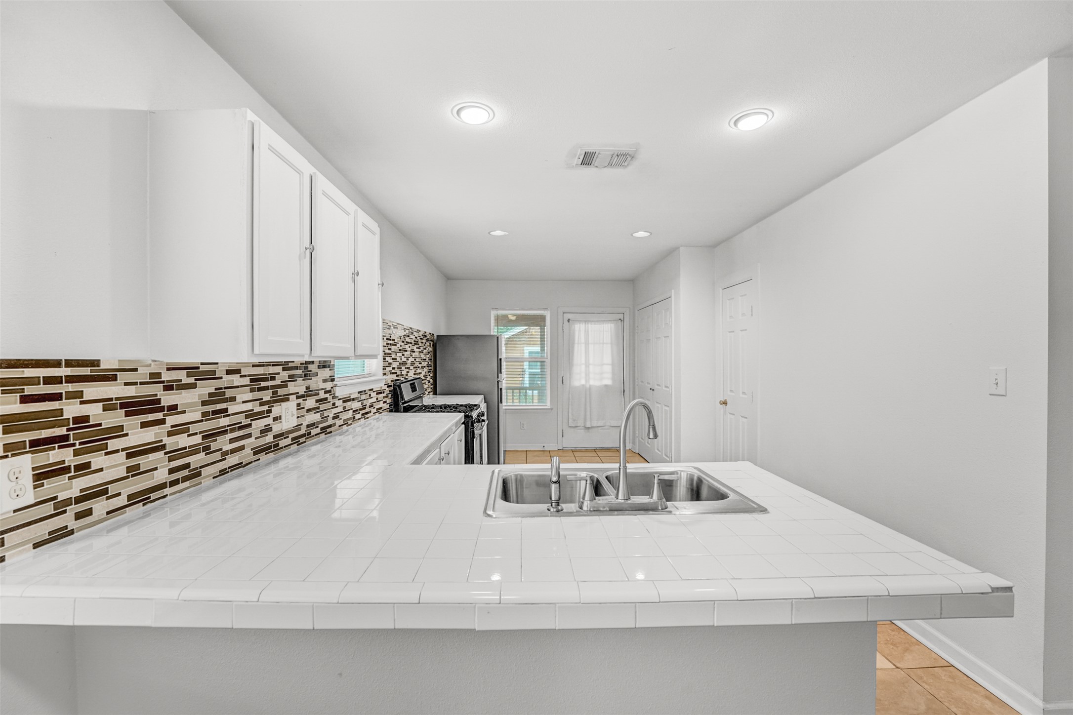 6906 Carver Avenue, Unit A Austin, TX 78752 - Photo 13 of 24 Kitchen featuring a peninsula, gas stove, white cabinets, recessed lighting, and tile countertops