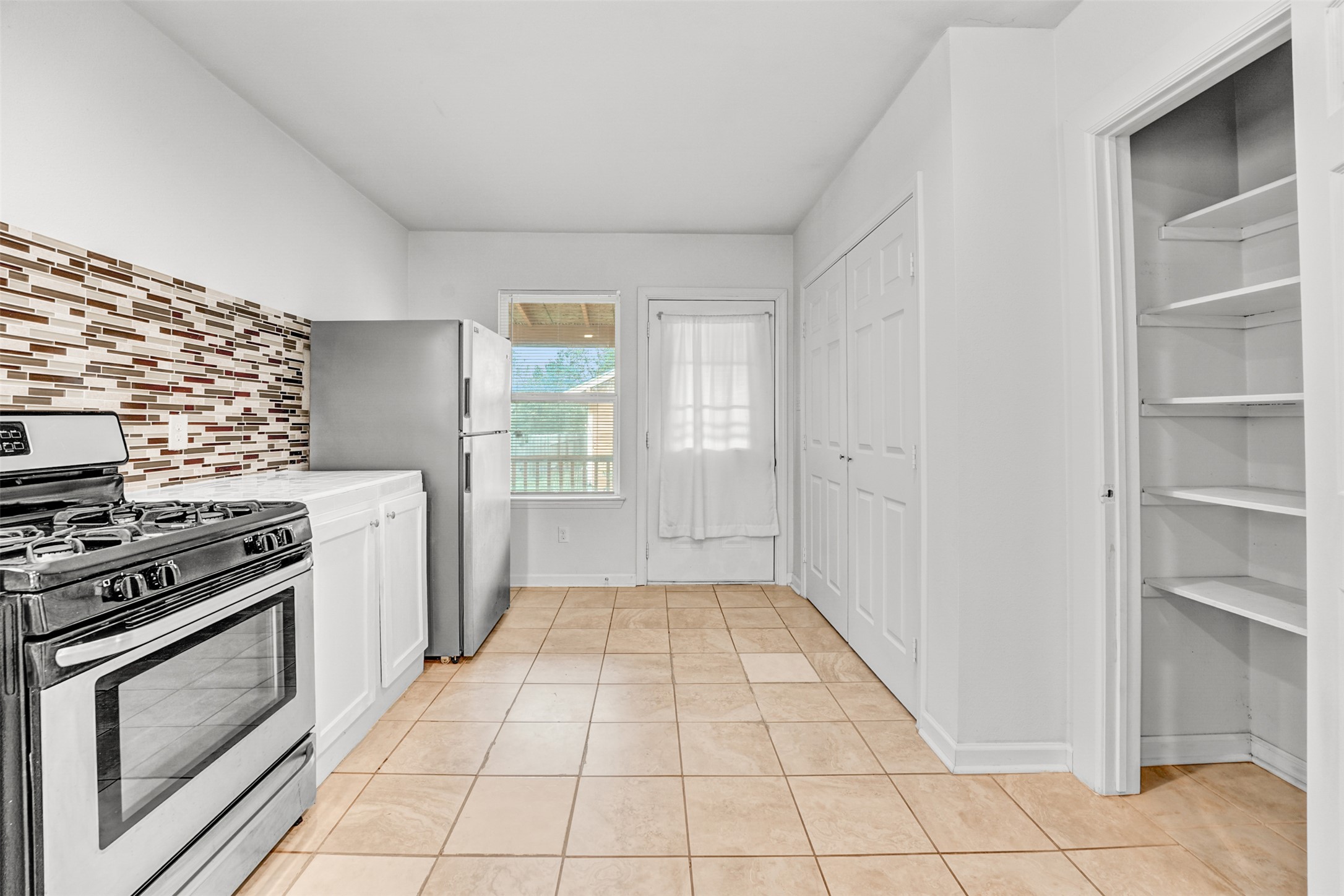 6906 Carver Avenue, Unit A Austin, TX 78752 - Photo 17 of 24 Kitchen with stainless steel appliances, light countertops, white cabinets, light tile patterned flooring, and backsplash