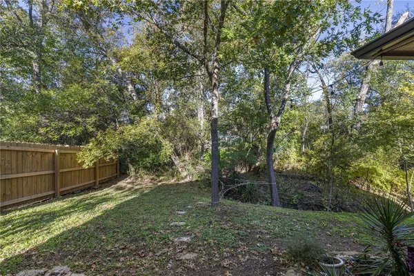a backyard of a house with lots of plants and large trees