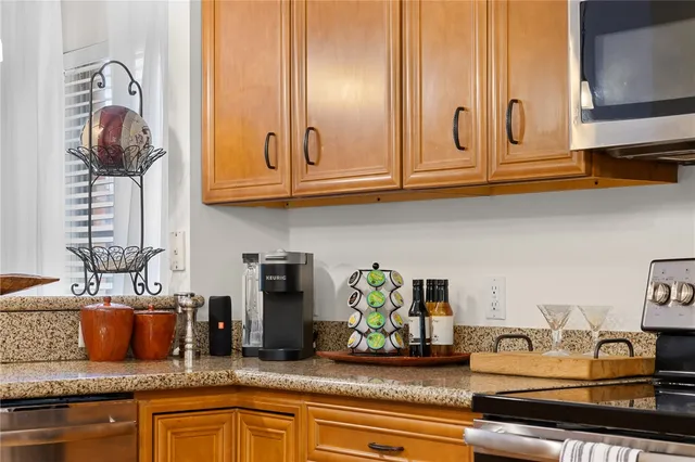 a kitchen with granite countertop lots of clutter and stainless steel appliances