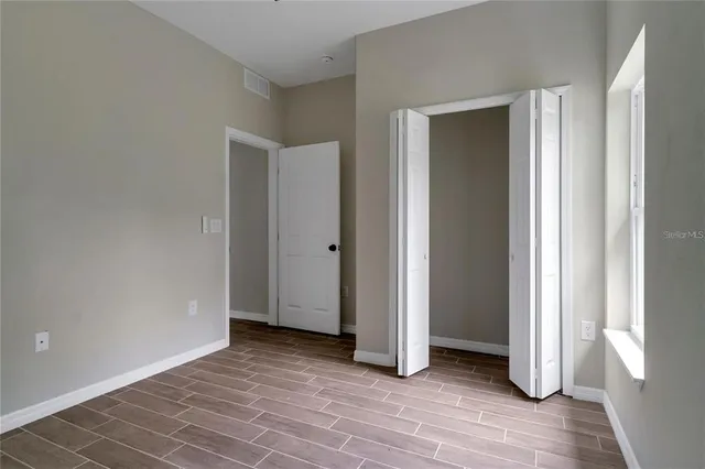 an empty room with wooden floor and closet
