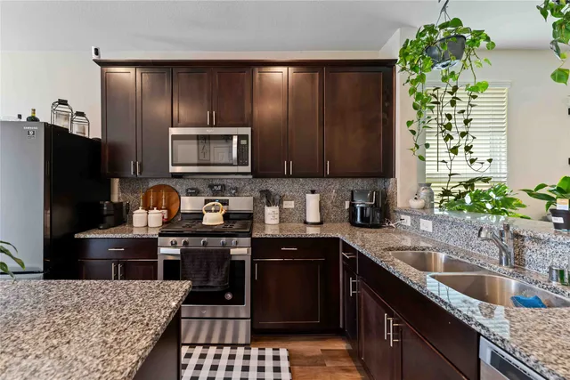 a kitchen with granite countertop a stove a sink and a microwave