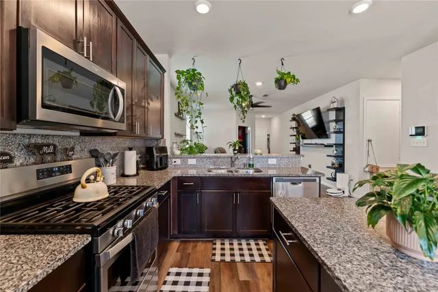 a kitchen with stainless steel appliances granite countertop a stove a sink and a microwave