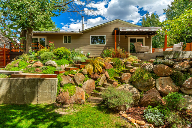 9706 Raintree Drive Sandy, UT 84092 - Photo 40 of 42 Multi-level landscaping featuring a rock garden, terraced wooden steps, and established greenery