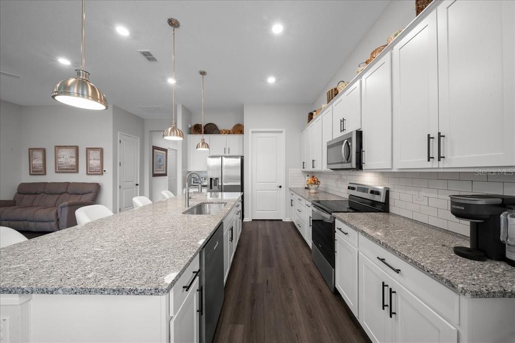 8750 Southwest 59th Ln Road Ocala, FL 34481 - Photo 29 of 41 a kitchen with granite countertop kitchen island stainless steel appliances a sink a stove top oven a counter space and cabinets