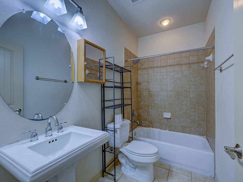 9707 Anderson Mill Road, Unit 22 Austin, TX 78750 - Photo 21 of 39 A well-appointed bathroom features a pedestal sink and tiled shower with a bright vanity mirror.