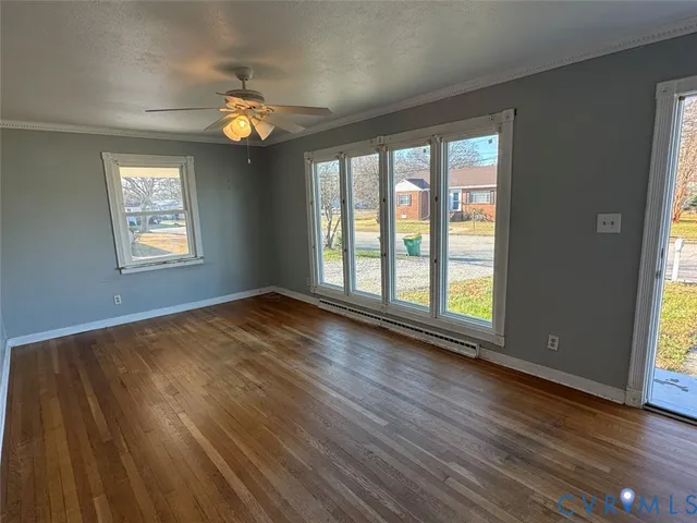 a view of an empty room with wooden floor and a window