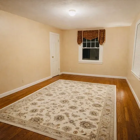 a view of empty room with wooden floor and window