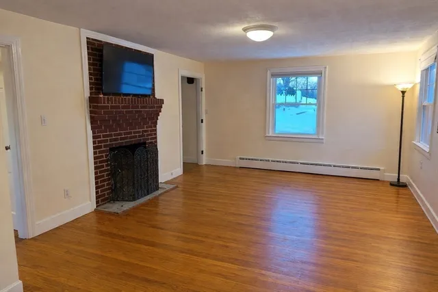 an empty room with wooden floor fireplace and windows