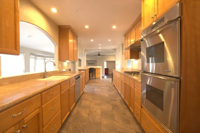 a large kitchen with kitchen island a large window a sink and stainless steel appliances